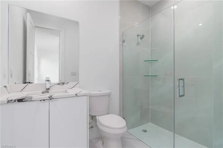 Bathroom featuring tile flooring, a shower with shower door, toilet, and vanity