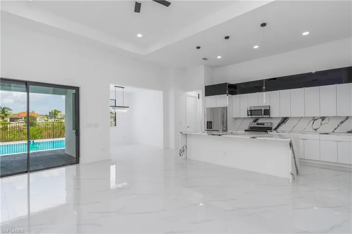 Kitchen with ceiling fan, decorative light fixtures, a kitchen island with sink, and appliances with stainless steel finishes