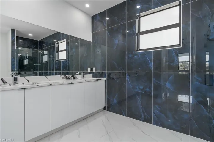 Bathroom featuring plenty of natural light, tile flooring, double sink, and tile walls
