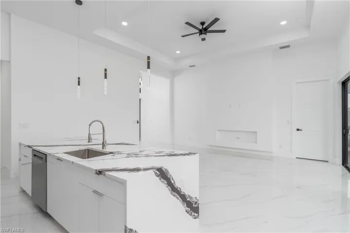 Kitchen with white cabinetry, a tray ceiling, decorative light fixtures, ceiling fan, and light tile floors