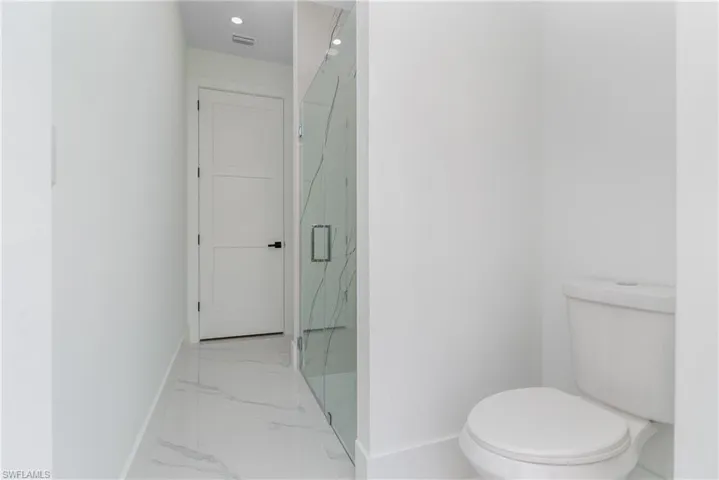 Bathroom with tile floors, an enclosed shower, and toilet