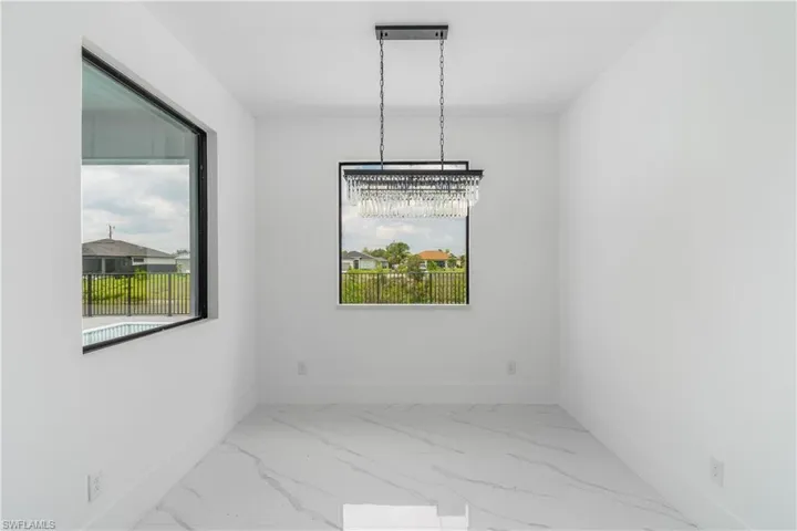 Tiled spare room with a chandelier