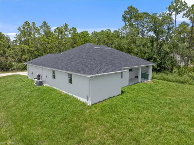 Rear view of property featuring central AC and a yard