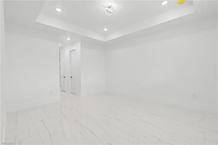 Empty room featuring light tile patterned floors and a tray ceiling