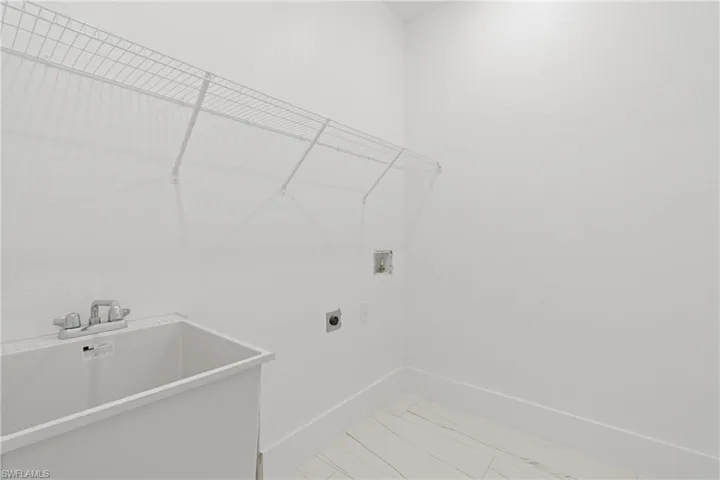 Washroom with tile patterned floors, sink, hookup for a washing machine, and electric dryer hookup