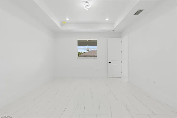 Tiled spare room featuring a tray ceiling
