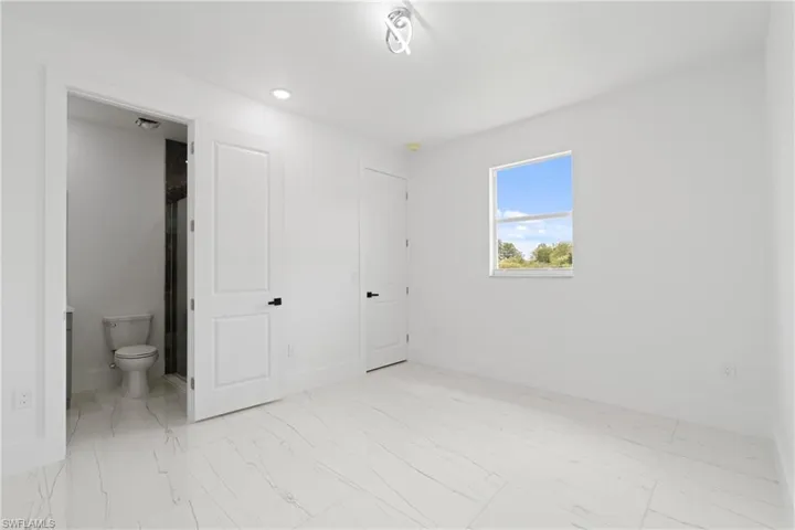 Unfurnished bedroom with connected bathroom and light tile patterned floors