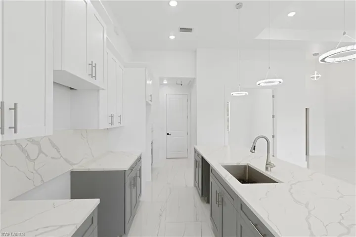 Kitchen with gray cabinets, light stone countertops, and sink