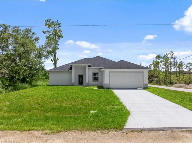 View of front of property featuring a garage and a front lawn