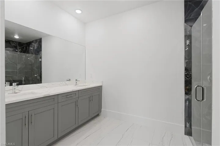 Bathroom featuring tile patterned flooring, walk in shower, and double vanity