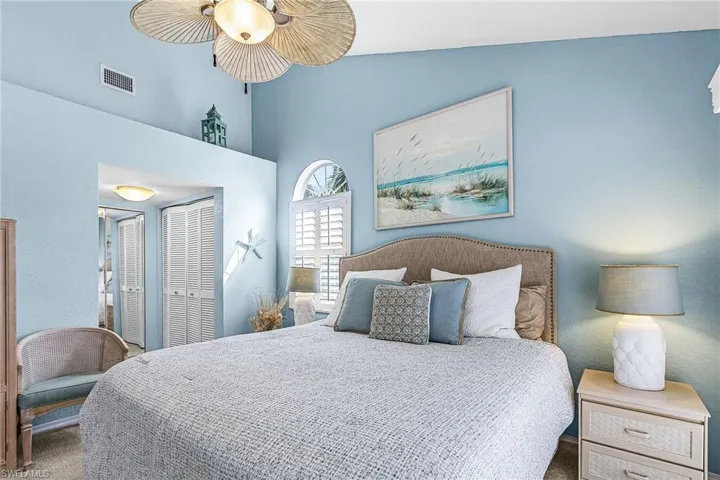 Carpeted bedroom featuring a textured wall, a closet, ceiling fan, and vaulted ceiling