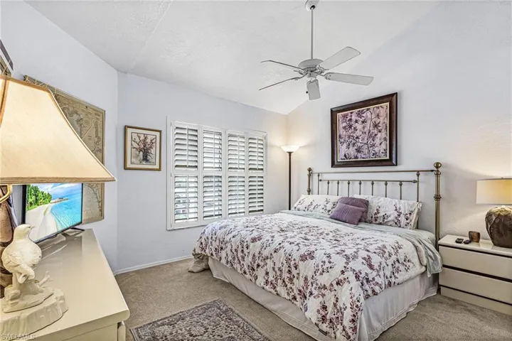 Carpeted bedroom with vaulted ceiling, a ceiling fan, and a textured ceiling