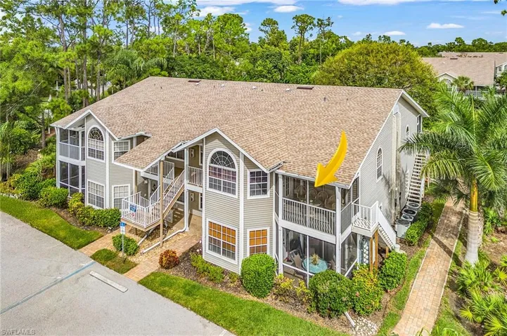 Back of house with stairs, roof with shingles, a sunroom, and view of wooded area