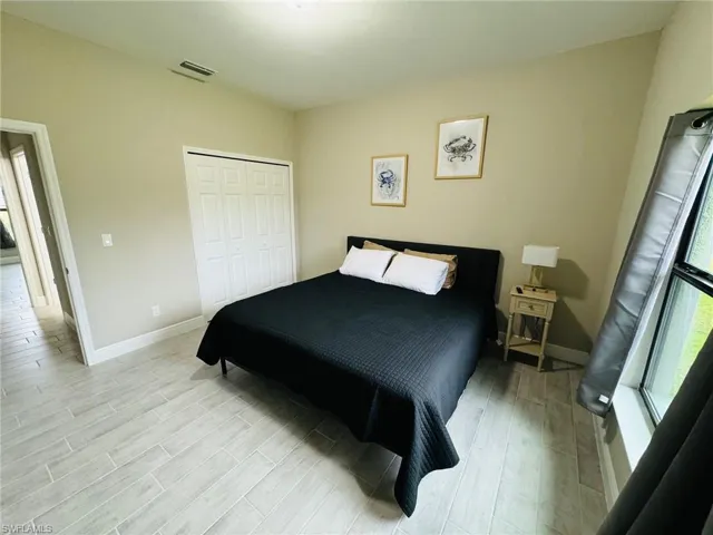 Bedroom with wood tiled floors, multiple windows, and a closet
