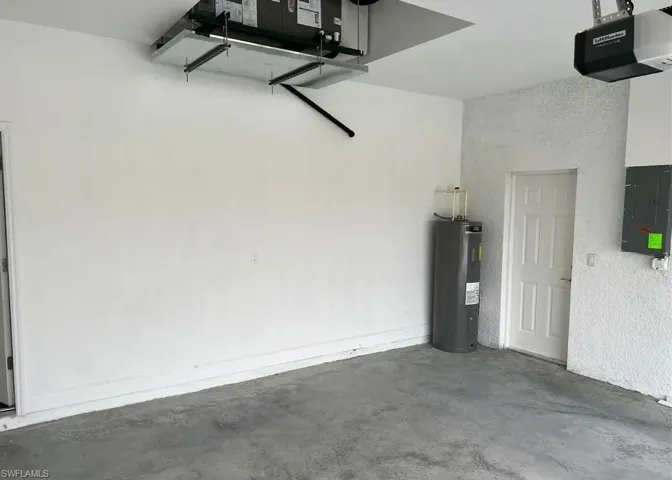Garage featuring a garage door opener, electric panel, and water heater