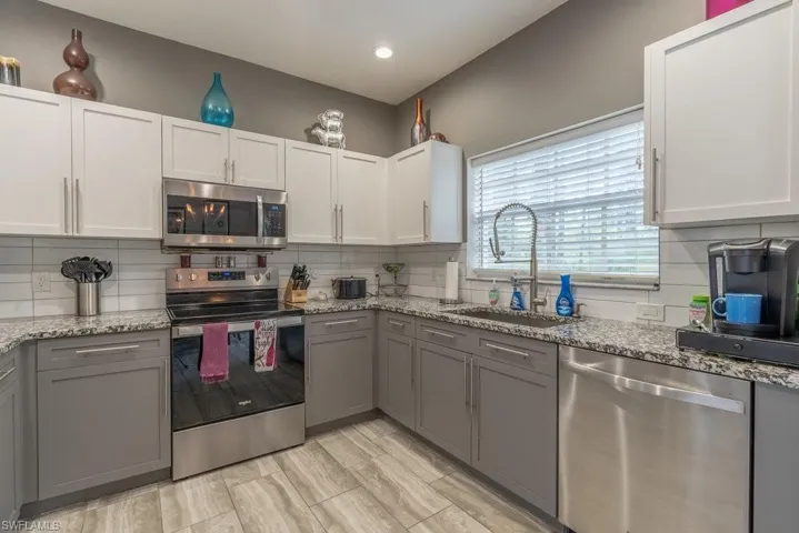 Kitchen with decorative backsplash, stainless steel appliances, sink, and white cabinets