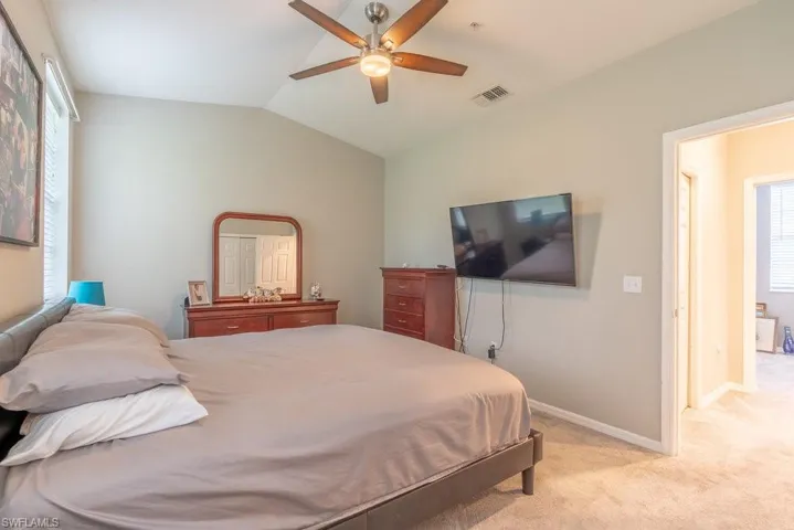 Carpeted bedroom featuring lofted ceiling and ceiling fan