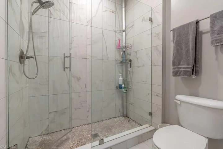 Bathroom featuring a shower with shower door and toilet