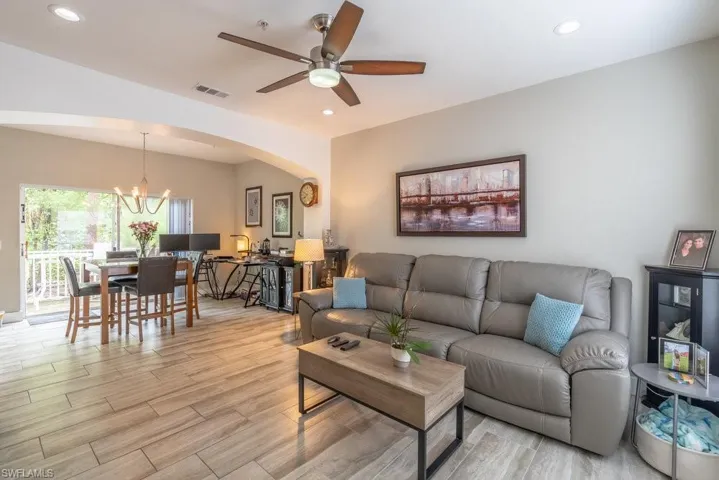 Living room with light hardwood / wood-style flooring and ceiling fan with notable chandelier
