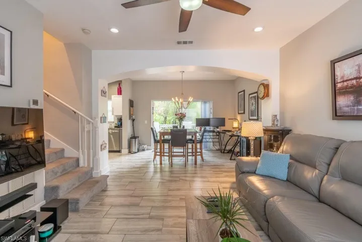 Living room featuring ceiling fan with notable chandelier and light hardwood / wood-style floors