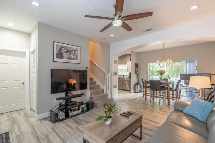 Living room with sink, ceiling fan with notable chandelier, and light wood-type flooring