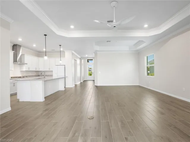 Living room with healthy amount of natural light, a tray ceiling, crown molding, light tole finished floors, and recessed lighting