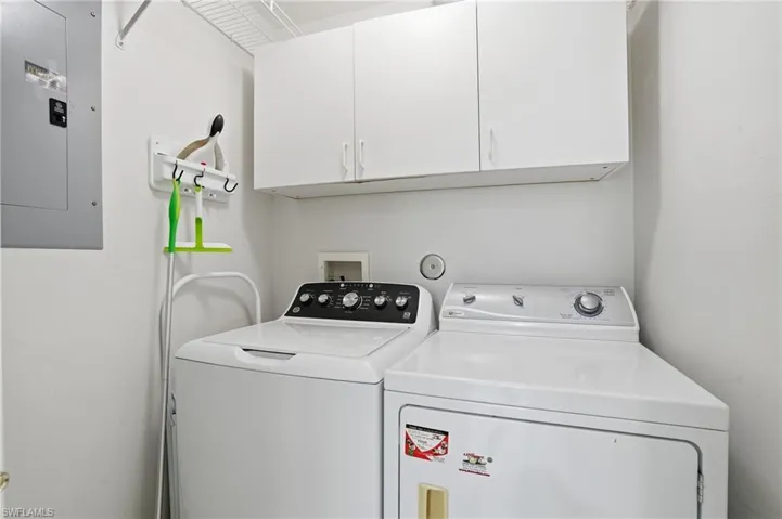 Washroom with electric panel, cabinet space, and washer and dryer