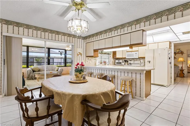 Dining space featuring light tile flooring, a textured ceiling, and ceiling fan with notable chandelier