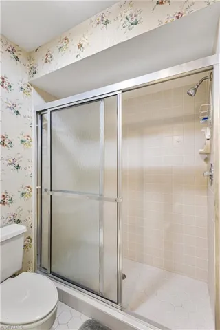 Bathroom featuring a shower with door, tile flooring, and toilet