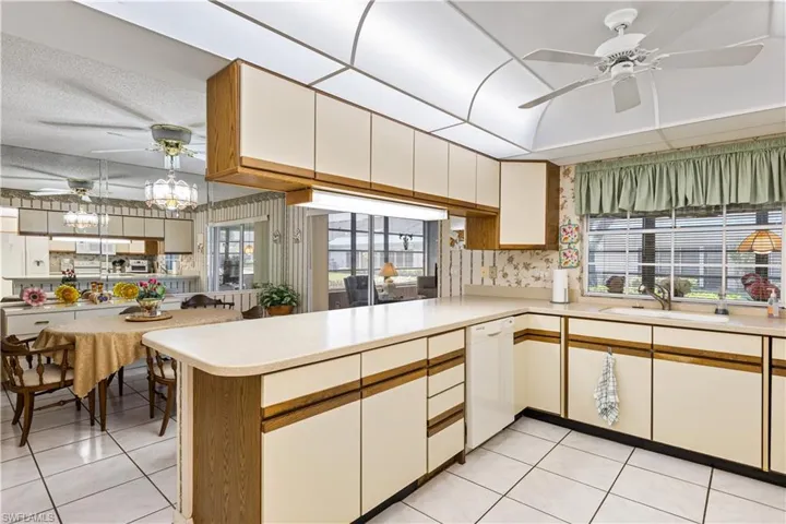 Kitchen with dishwasher, ceiling fan, light tile flooring, and kitchen peninsula