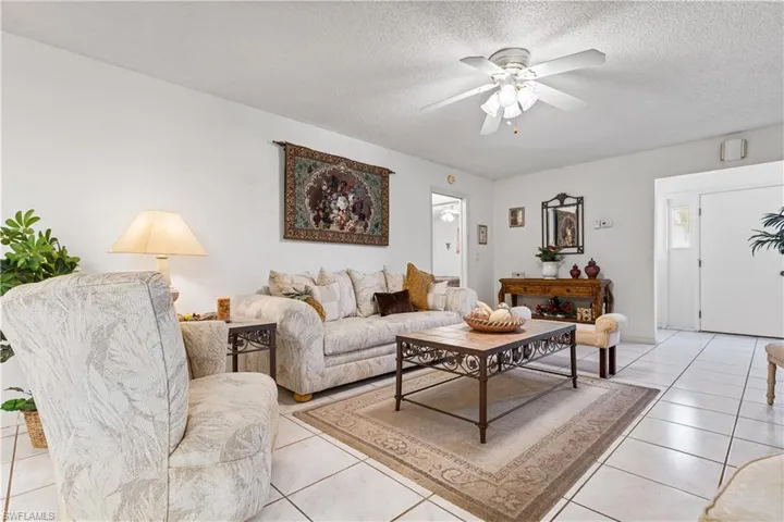 Living room featuring ceiling fan, a textured ceiling, and light tile floors