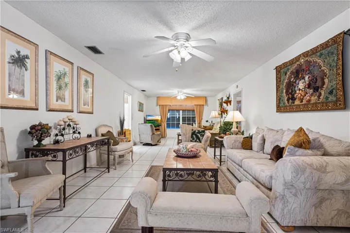 Tiled living room featuring ceiling fan and a textured ceiling