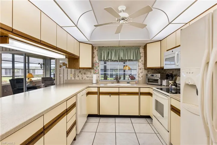 Kitchen with plenty of natural light, white appliances, and tasteful backsplash