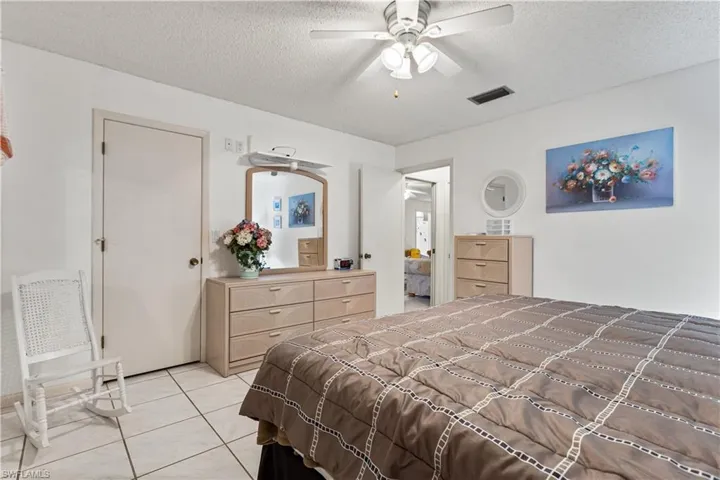 Bedroom with a textured ceiling, ceiling fan, and light tile flooring