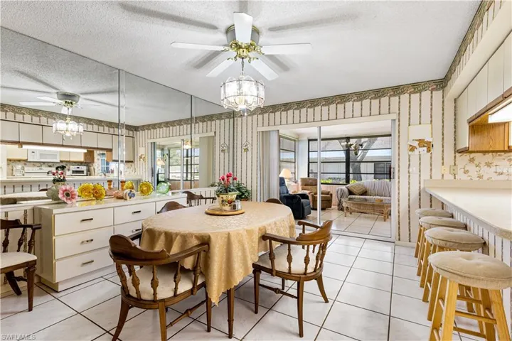 Dining area featuring ceiling fan with notable chandelier, a textured ceiling, and light tile floors