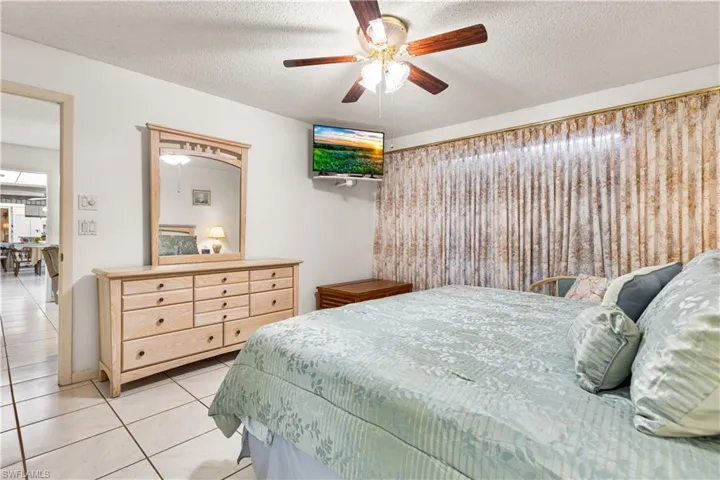 Bedroom featuring a textured ceiling, ceiling fan, and light tile floors