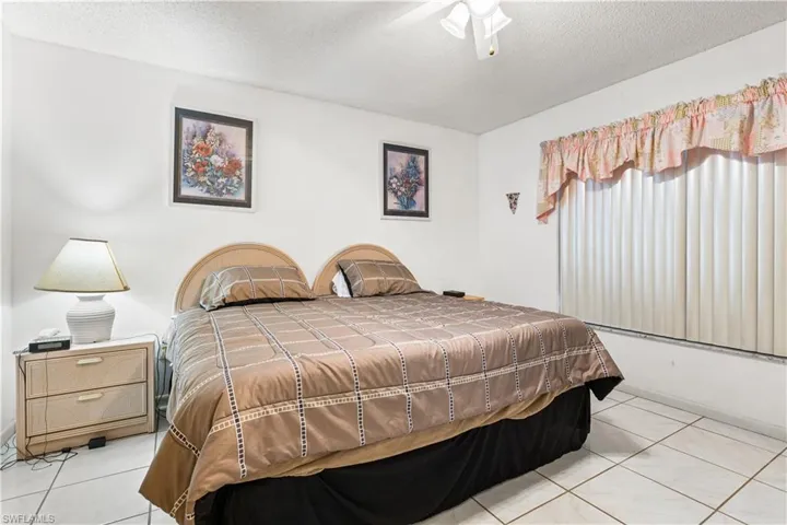 Tiled bedroom featuring ceiling fan and a textured ceiling