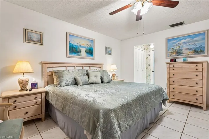 Bedroom featuring ceiling fan, a textured ceiling, and light tile floors