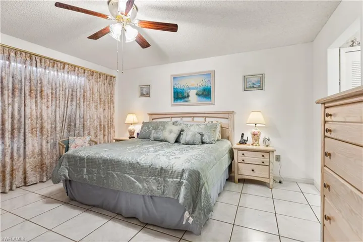 Bedroom featuring a textured ceiling, ceiling fan, and light tile floors