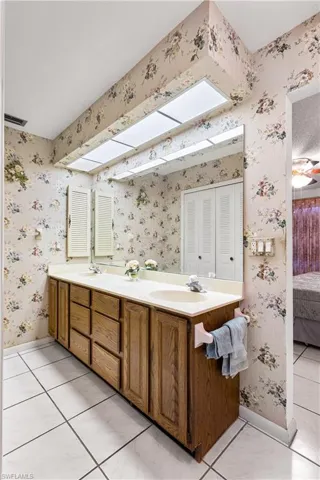 Bathroom with vanity with extensive cabinet space, dual sinks, and tile floors