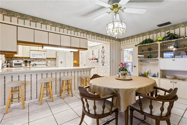Dining area featuring light tile floors, a textured ceiling, and ceiling fan with notable chandelier