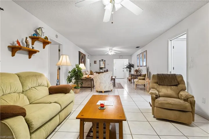 Tiled living room with ceiling fan and a textured ceiling