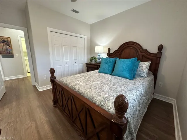 Guest Bedroom Featuring a Queen Size Bed with dark hardwood / wood-style floors and a closet