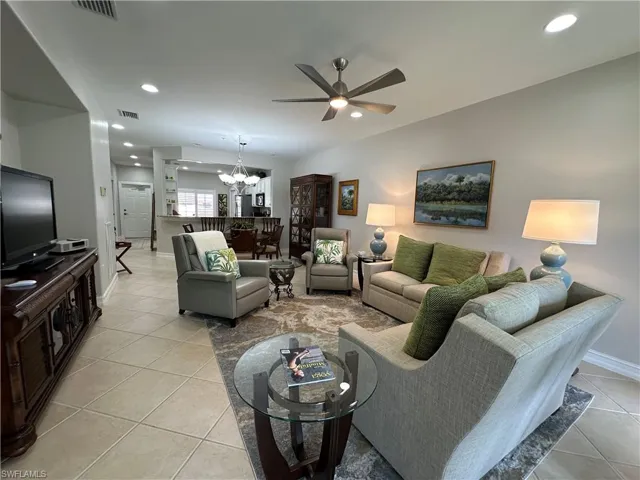 Tiled living room featuring ceiling fan with notable chandelier