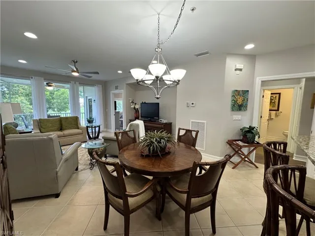 Dining space with ceiling fan with notable chandelier and light tile patterned floors