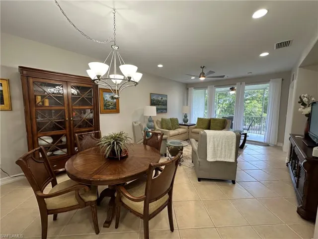 Dining space with ceiling fan with notable chandelier and light tile patterned floors