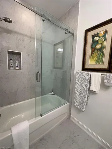 Guest Bathroom with bath / shower combo with glass door and tile patterned floors