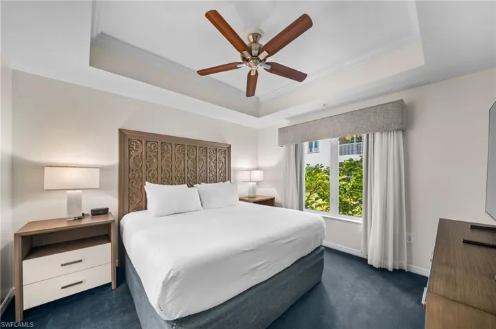 Bedroom featuring ornamental molding, ceiling fan, dark carpet, and a tray ceiling