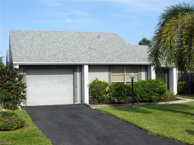 Ranch-style house with roof with shingles, driveway, an attached garage, and a front yard
