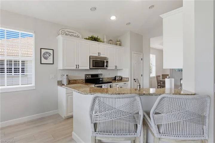 Kitchen featuring white cabinetry, stainless steel appliances, granite countertops, and a subway tile backsplash